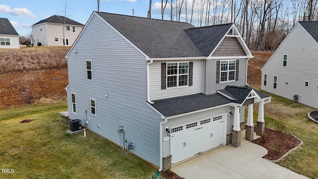 exterior space with central air condition unit, a yard, a garage, and roof with shingles