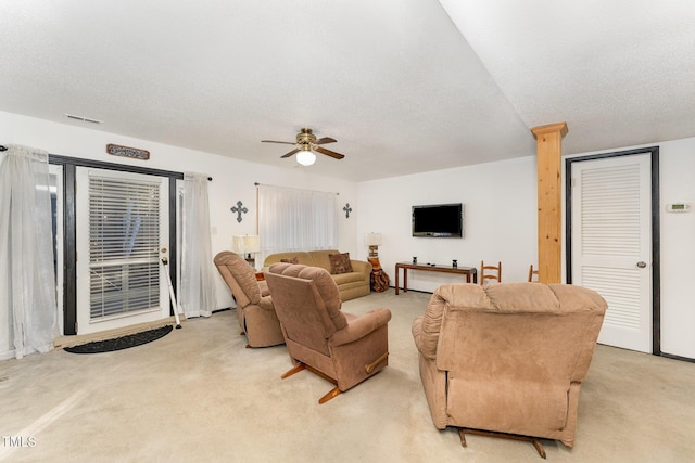 living area with a textured ceiling, a ceiling fan, visible vents, and light carpet