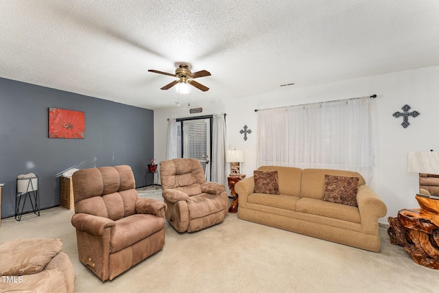 living area with carpet, ceiling fan, and a textured ceiling