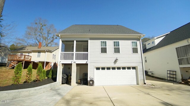 view of front of house with a shingled roof, concrete driveway, an attached garage, and a sunroom