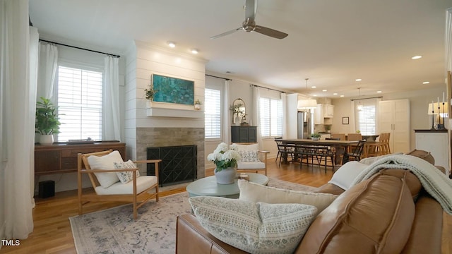 living area featuring recessed lighting, a healthy amount of sunlight, a fireplace, and light wood-style floors