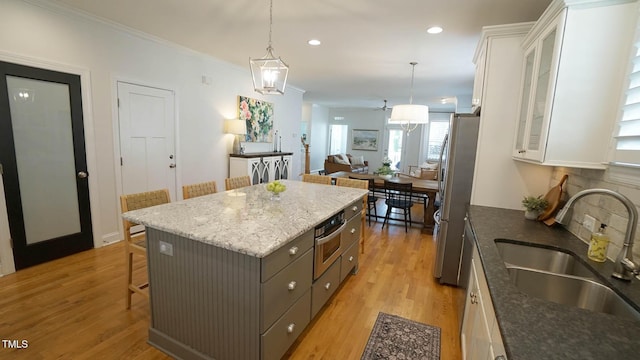 kitchen featuring light wood finished floors, white cabinets, freestanding refrigerator, and a sink