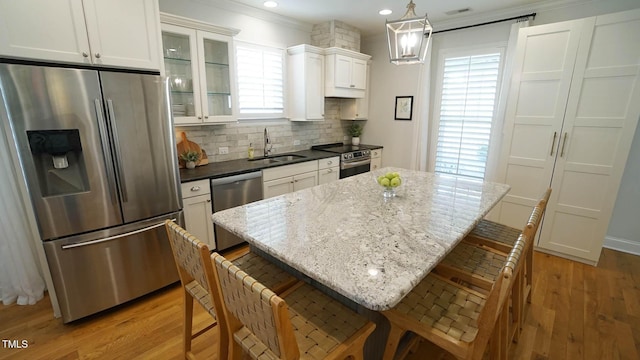 kitchen featuring tasteful backsplash, light wood-type flooring, appliances with stainless steel finishes, a kitchen breakfast bar, and a sink