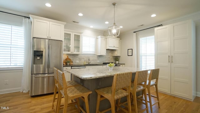 kitchen featuring visible vents, a sink, light wood-style floors, appliances with stainless steel finishes, and a center island