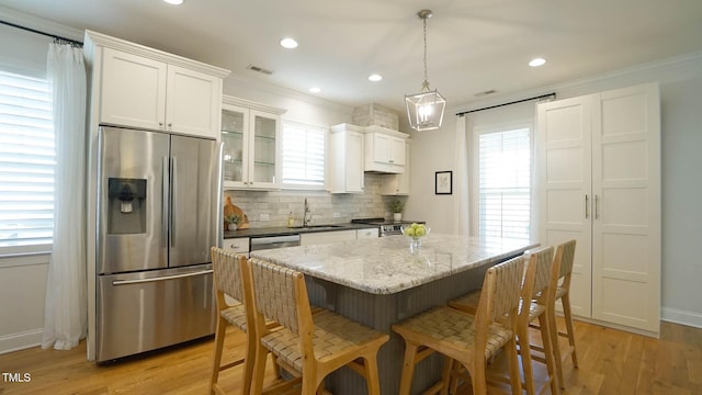 kitchen with a sink, decorative backsplash, appliances with stainless steel finishes, and light wood-style flooring