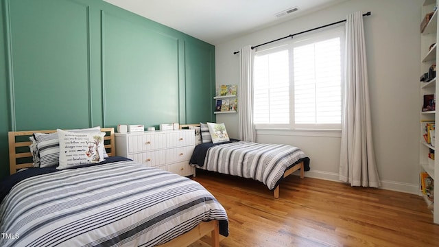 bedroom with visible vents, light wood-type flooring, and baseboards