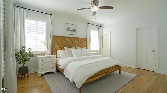 bedroom with baseboards, multiple windows, light wood-style floors, and a ceiling fan