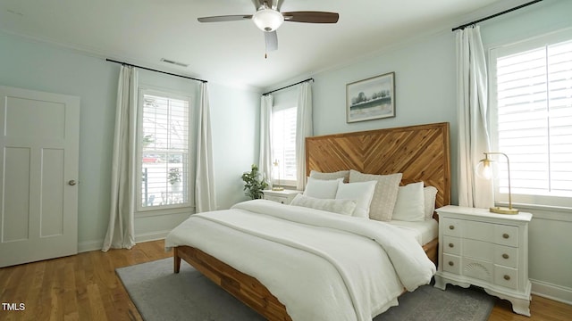 bedroom featuring visible vents, multiple windows, and wood finished floors