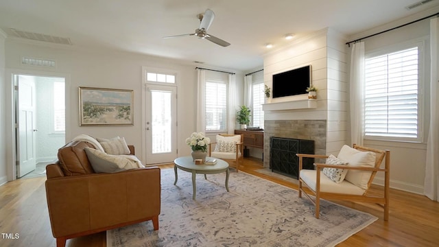 living area featuring a fireplace with flush hearth, visible vents, a wealth of natural light, and light wood-type flooring