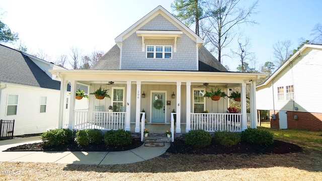 view of front of house with covered porch, board and batten siding, a ceiling fan, and roof with shingles