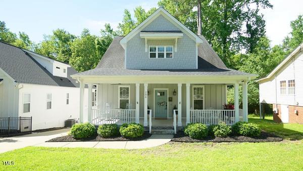 view of front facade featuring board and batten siding, a porch, a front yard, and central air condition unit
