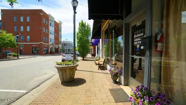 view of asphalt street with street lighting, curbs, and sidewalks