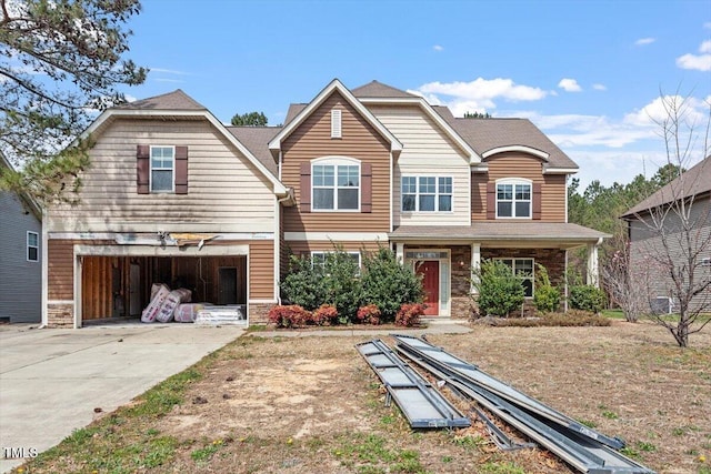 view of front of home with concrete driveway, stone siding, a garage, and a gambrel roof