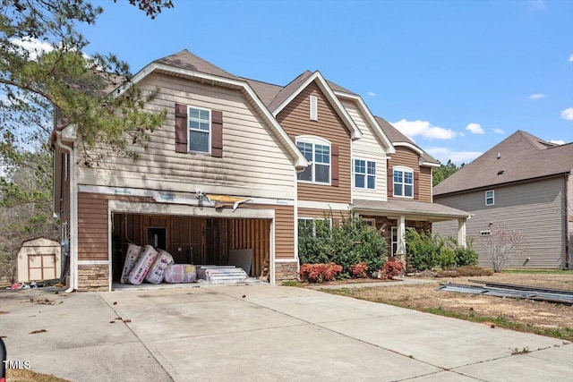 craftsman-style home with stone siding, driveway, and a garage