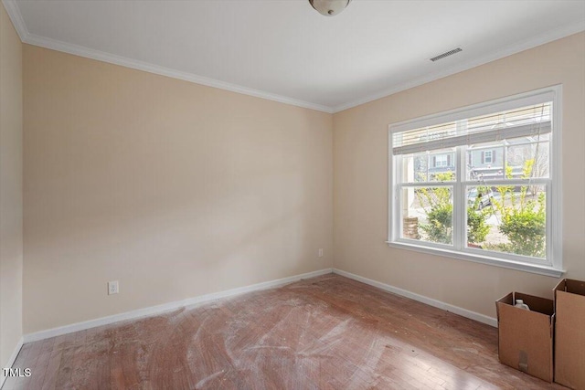 spare room featuring wood finished floors, visible vents, baseboards, and ornamental molding