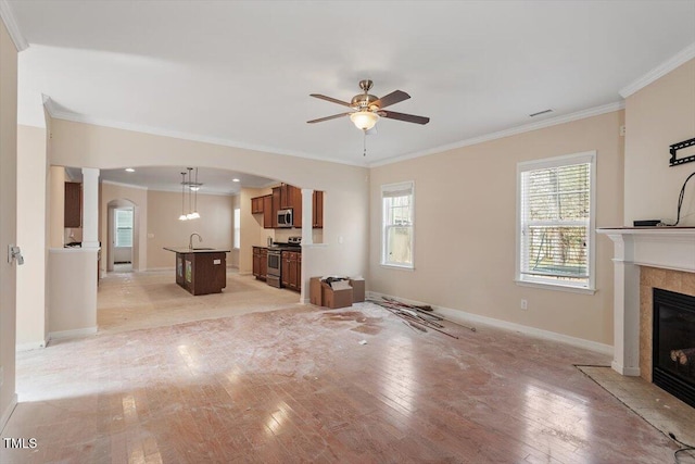 unfurnished living room with a fireplace with flush hearth, arched walkways, ornamental molding, ceiling fan, and light wood-style floors