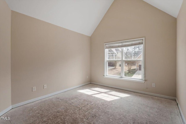 empty room with baseboards and high vaulted ceiling