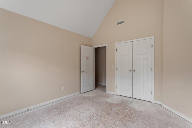 unfurnished bedroom featuring baseboards, visible vents, a closet, and high vaulted ceiling