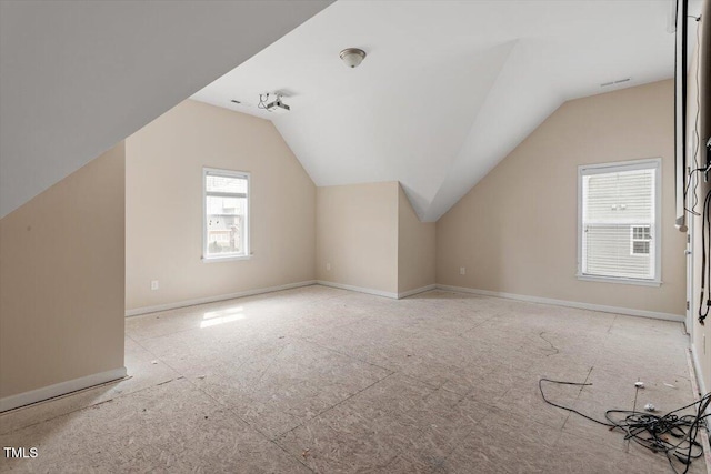 bonus room with lofted ceiling and baseboards