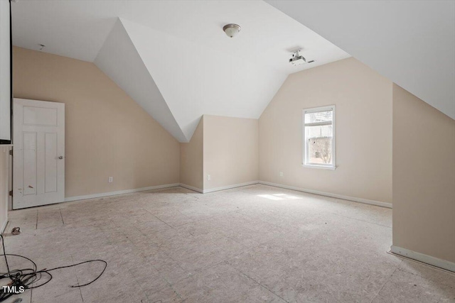 additional living space with baseboards and vaulted ceiling