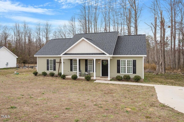 view of front of house with a porch, a front yard, and roof with shingles