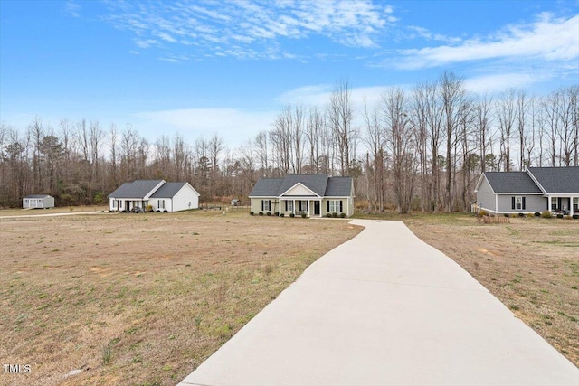 view of front of property featuring an outbuilding, covered porch, concrete driveway, and a front lawn