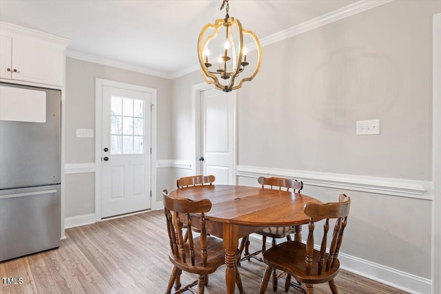 dining space featuring light wood-style flooring, baseboards, an inviting chandelier, and ornamental molding