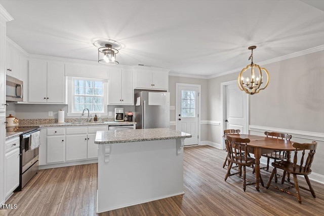 kitchen with a sink, a kitchen island, appliances with stainless steel finishes, and light wood-style flooring