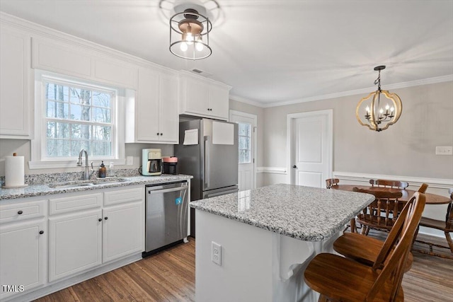 kitchen with crown molding, wood finished floors, white cabinets, stainless steel appliances, and a sink