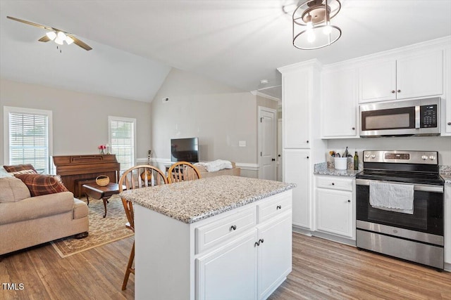 kitchen featuring light wood-type flooring, lofted ceiling, white cabinets, appliances with stainless steel finishes, and open floor plan