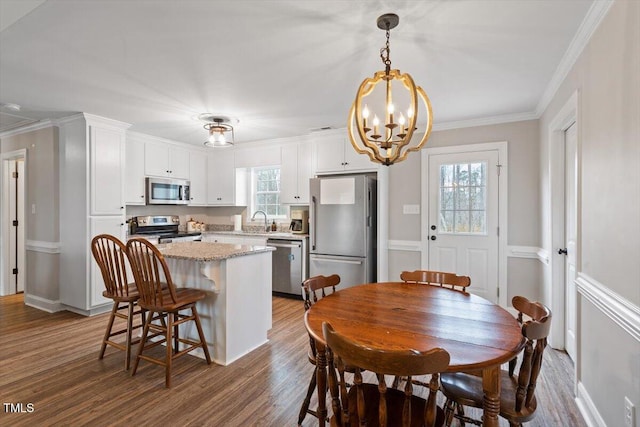 dining room featuring wood finished floors, a notable chandelier, and ornamental molding