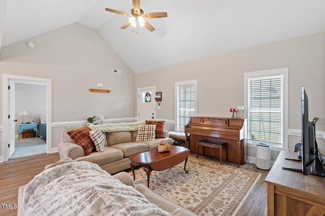 living area with light wood finished floors, visible vents, a wealth of natural light, and high vaulted ceiling