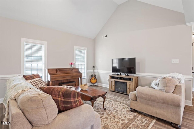 living room with visible vents, high vaulted ceiling, baseboards, and wood finished floors