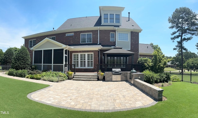 rear view of house featuring a lawn, fence, exterior kitchen, a sunroom, and a patio area