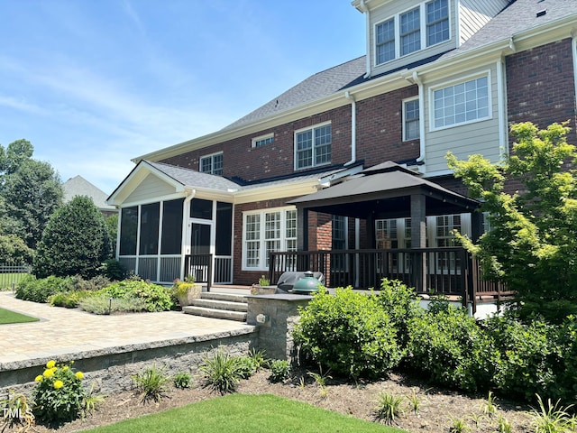 back of house featuring a gazebo, a patio, brick siding, and a sunroom