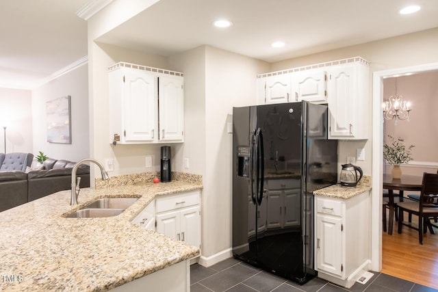 kitchen with ornamental molding, a sink, light stone counters, white cabinetry, and black refrigerator with ice dispenser