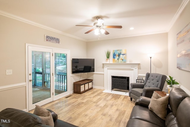 living room featuring visible vents, a fireplace with flush hearth, light wood-type flooring, ornamental molding, and a ceiling fan