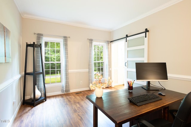 home office with a barn door, a healthy amount of sunlight, and wood finished floors