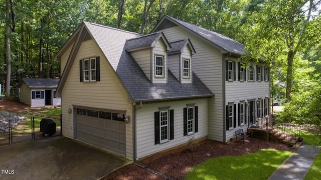 view of front of property featuring an attached garage, driveway, roof with shingles, and fence