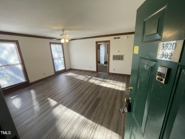 unfurnished living room featuring visible vents, wood finished floors, baseboards, and ornamental molding