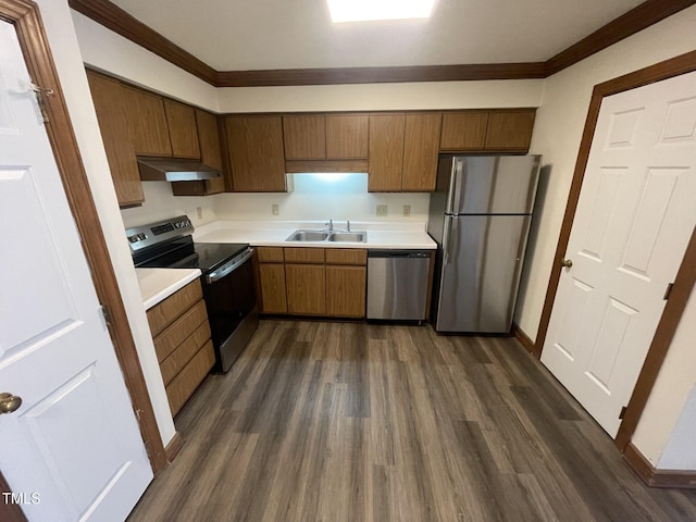 kitchen with a sink, under cabinet range hood, appliances with stainless steel finishes, light countertops, and dark wood-style flooring