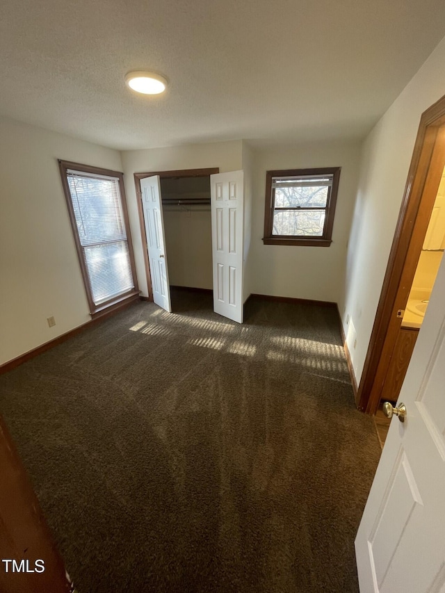 unfurnished bedroom featuring a closet, baseboards, and dark carpet