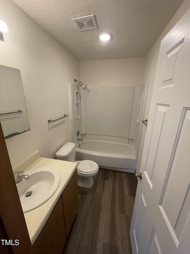 full bathroom with visible vents, toilet, a textured ceiling, wood finished floors, and vanity