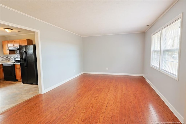 unfurnished living room featuring crown molding, light wood-style flooring, and baseboards