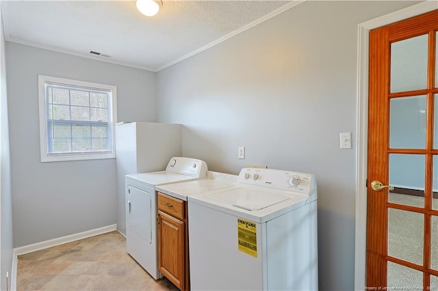 washroom featuring visible vents, baseboards, cabinet space, crown molding, and washer and clothes dryer