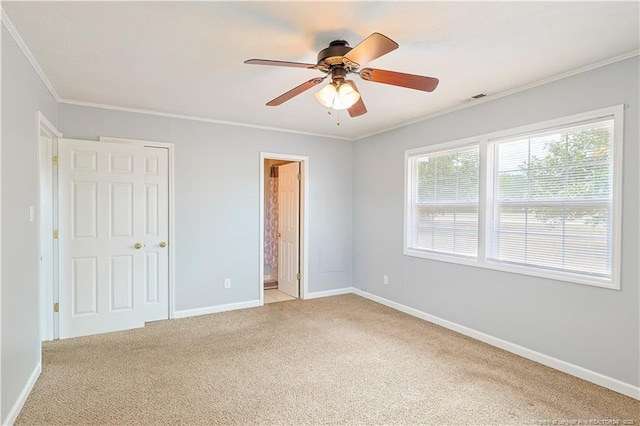 unfurnished bedroom featuring visible vents, baseboards, ornamental molding, light carpet, and ensuite bath