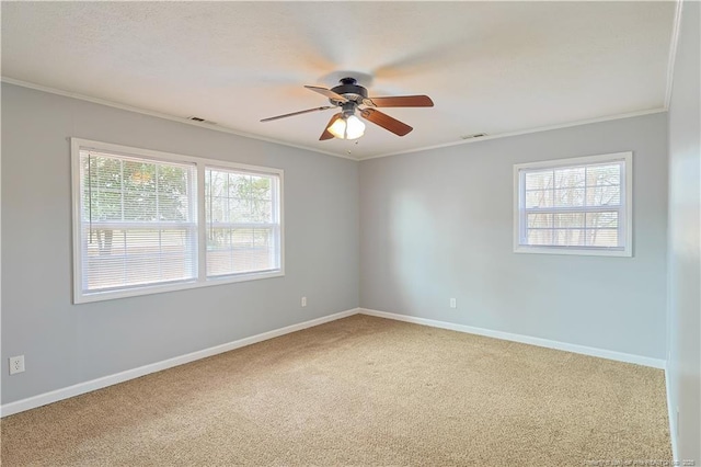 carpeted empty room featuring visible vents, baseboards, ceiling fan, and ornamental molding