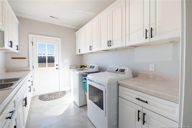 washroom featuring visible vents, cabinet space, separate washer and dryer, a sink, and crown molding