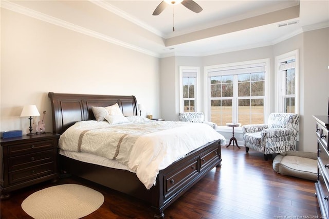 bedroom featuring visible vents, a ceiling fan, a tray ceiling, dark wood finished floors, and crown molding