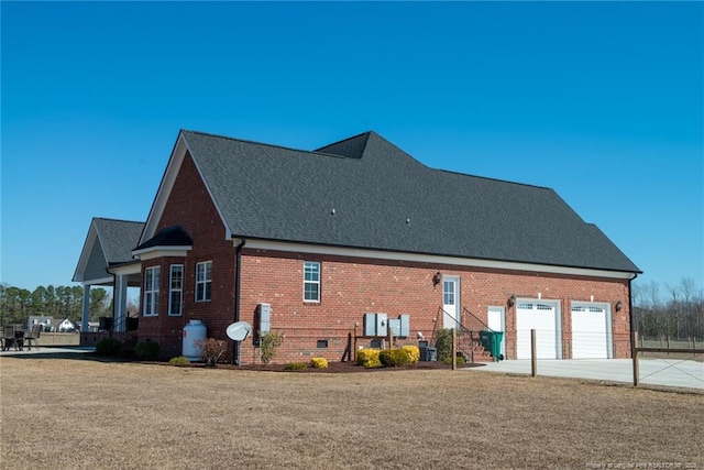 view of side of property with a garage, brick siding, driveway, and a shingled roof